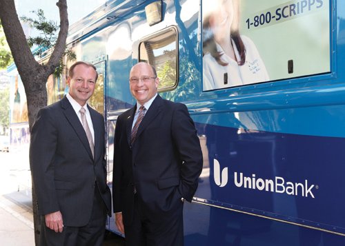 Bruce Breslau, left, of Union Bank, and John Engle, of Scripps Health, stand next to the Mobile Medical Unit, which will help serve health care needs in the community.