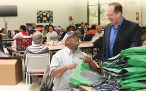 Mark Berger, CEO of Partnerships With Industry, speaks with a client at work at PWI’s Mission Valley location. Berger’s organization brings together employers and people with developmental disabilities.