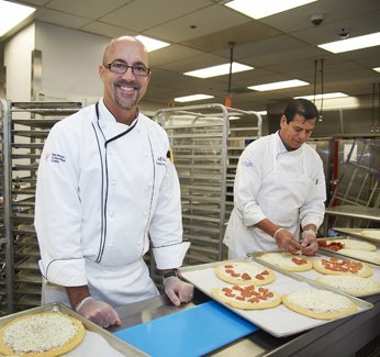 Jeff Leidy, the San Diego Convention Center’s assistant general manager of food and beverage, center, prepares pizzas in the center’s kitchen with lead chef Rey Alcaraz. Comic-Con is notable for the ‘sheer volume’ of food prepared and sold, Leidy says.