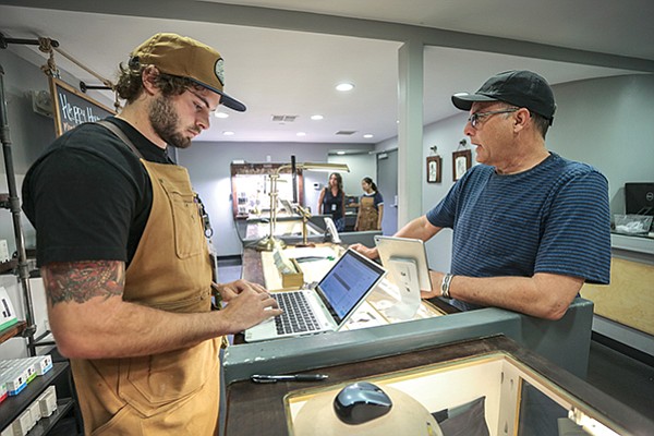 OutCo Assistant Manager Rhettry Griebel, left, uses a cannabis-specific retail operations platform developed by Yobi, a local software startup, to track sales at the dispensary in El Cajon.