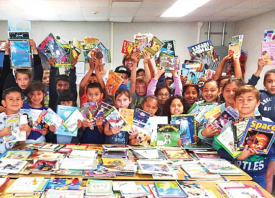 Children hold up books donated to San Diego Oasis for its Intergenerational Literacy Tutoring Program. Photo courtesy of San Diego Oasis