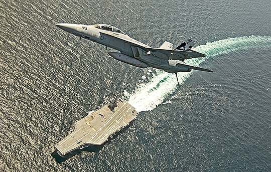 An F/A-18F Super Hornet flies over the USS Gerald R. Ford in the Atlantic Ocean in July 2017. Photo by Erik Hildebrandt courtesy of U.S. Navy